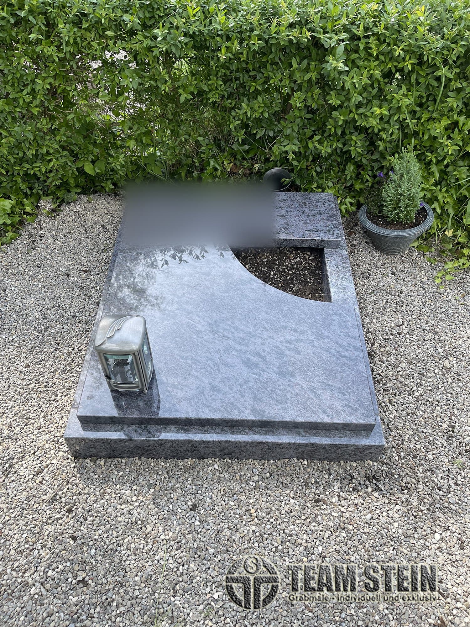 Liegende Grabplatte aus blauem Granit mit bogenförmiger Pflanzöffnung und Laterne